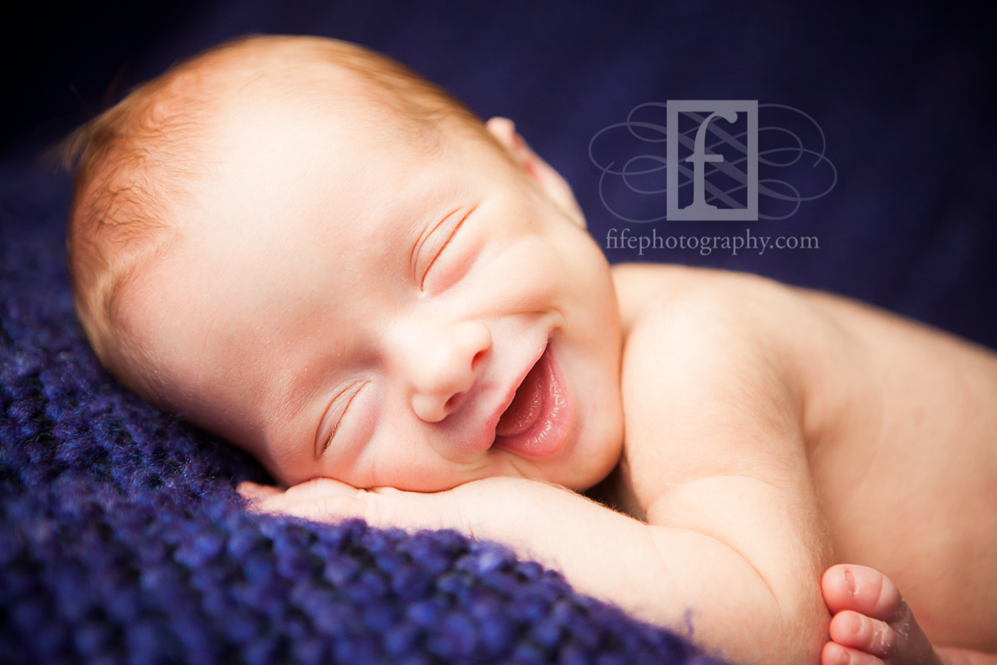 newborn baby smiling on blue blanket